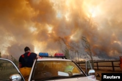 FILE - A fireman climbs down from his truck as a bushfire approaches the town of Labertouche, 90 km (56 miles) east of Melbourne, Feb. 7, 2009.