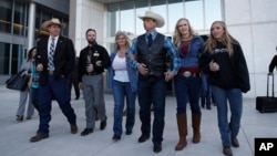 FILE - From left, Ammon Bundy, Ryan Payne, Jeanette Finicum, widow of Robert "LaVoy" Finicum, Ryan Bundy, Angela Bundy, wife of Ryan Bundy and Jamie Bundy, daughter of Ryan Bundy, walk out of a federal courthouse in Las Vegas, Dec. 20, 2017.