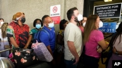 Pasajeros aguardan en una larga fila para hacerse la prueba de COVID-19 en el aeropuerto internacional de Fort Lauderdale debido a la cancelación de varios vuelos porque los pasajeros debieron hacerse nuevamente un examen. 