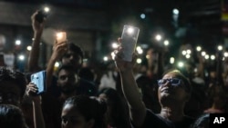 Orang-orang menyalakan senter ponsel mereka saat mengikuti unjuk rasa tengah malam untuk menuntut keadilan bagi Dokter yang dibunuh di Kolkata, India, Minggu, 8 September 2024.