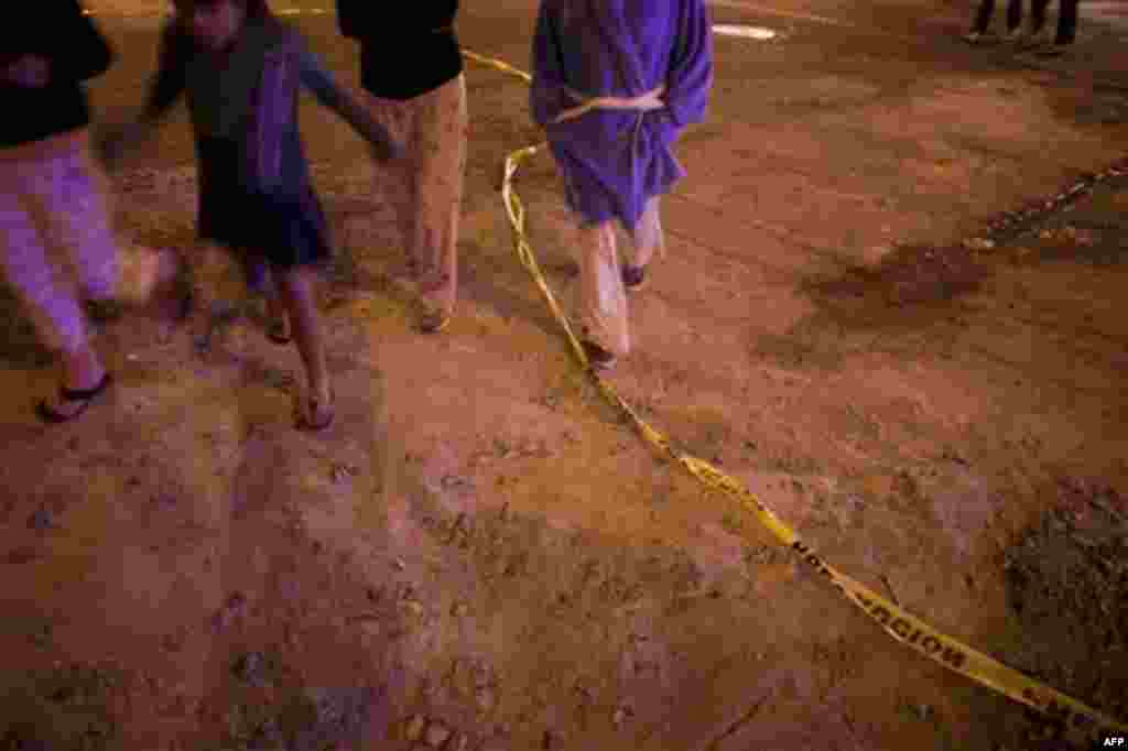 Children walk past police tape near a mini-market in the Zona Norte area of Tijuana, Mexico, late Tuesday Nov. 16, 2010. According to residents at the scene, a man was shot to death in the store. (AP Photo/Guillermo Arias)