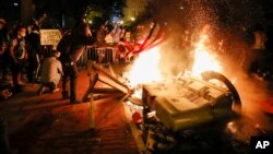 Demonstran membakar sesuatu ketika melakukan protes atas kematian George Floyd di dekat Gedung Putih, Washington DC hari Minggu malam (31/5). 