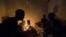 FILE - Friends talk by candlelight during load shedding in Embo, South Africa, March 18, 2019. 