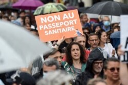 A woman holds a placard reading "No to the health pass" during a demonstration against the compulsory vaccination for certain workers and the mandatory use of a health pass called for the French government, in Nantes, France, July 24, 2021.