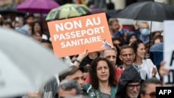 A woman holds a placard reading "No to the health pass" during a demonstration against the compulsory vaccination for certain workers and the mandatory use of a health pass called for the French government, in Nantes, France, July 24, 2021. 