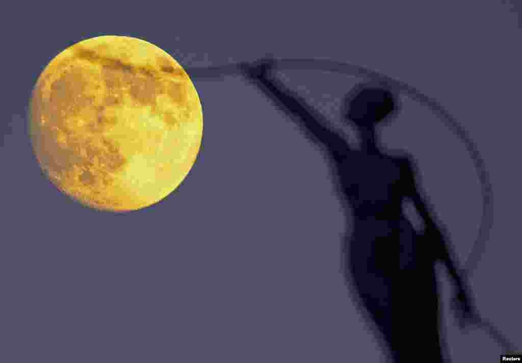 A statue is seen silhouetted against the moon in Brussels, Belgium, Sept. 26, 2015.