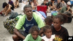 Local resident Selwyn Hughes (C) sits with his children outside an emergency cyclone shelter after it was declared full and the gate locked in Cairns, February 02, 2011