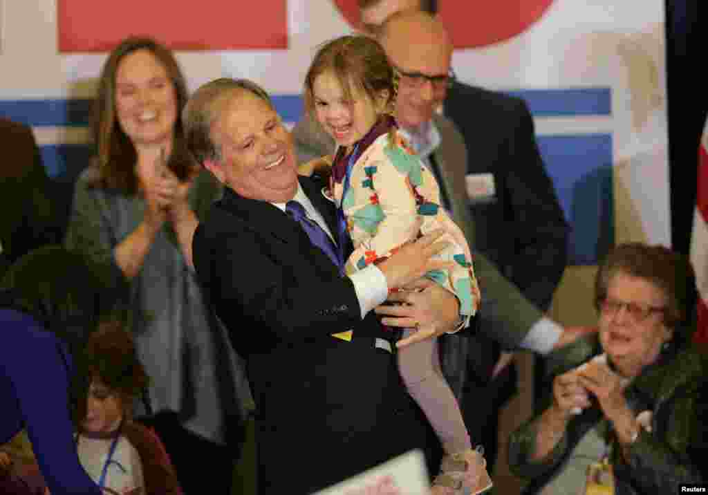 داگ جونز، سناتور منتخب آلاباما پیروزی غیرقابل انتظار خود را به همراه نوه اش در جمع هواداران جشن می گیرد.