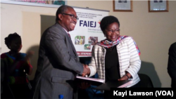 Echange de document entre le ministre de la communication et celle de l'emploi des jeunes, à Lomé, Togo, le 15 janvier 2017. (VOA/Kayi Lawson)