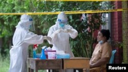 ရန်ကုန်မြို့ Quarantine စင်တာတခုမှာ COVID 19 ရှိ၊ မရှိ စစ်ဆေးပေးနေတဲ့ PPE ဝတ်စုံများ ဝတ်ထားတဲ့ ကျန်းမာရေးဝန်ထမ်းများ။ (အောက်တိုဘာ ၀၇၊ ၂၀၂၀)