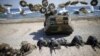 South Korean (blue headbands) and U.S. Marines take positions as amphibious assault vehicles of the South Korean Marine Corps fire smoke bombs during a U.S.-South Korea joint landing operation drill in Pohang, South Korea, March 12, 2016. 