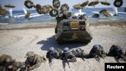 South Korean (blue headbands) and U.S. Marines take positions as amphibious assault vehicles of the South Korean Marine Corps fire smoke bombs during a U.S.-South Korea joint landing operation drill in Pohang, South Korea, March 12, 2016. 