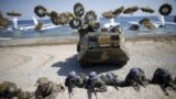 South Korean (blue headbands) and U.S. Marines take positions as amphibious assault vehicles of the South Korean Marine Corps fire smoke bombs during a U.S.-South Korea joint landing operation drill in Pohang, South Korea, March 12, 2016. 