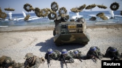 South Korean (blue headbands) and U.S. Marines take positions as amphibious assault vehicles of the South Korean Marine Corps fire smoke bombs during a U.S.-South Korea joint landing operation drill in Pohang, South Korea, March 12, 2016.
