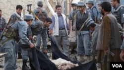 Polisi Afghanistan menutupi jenazah korban tewas dalam ledakan bom di Kunduz, Afghanistan utara.