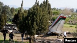 Các điều tra viên đứng cạnh xác chiếc phi cơ quân sự của Libya bị rơi gần thị trấn Grombalia, Libya, 21/2/14