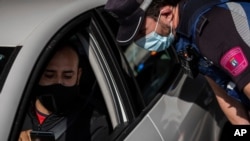 Un policía local detiene un vehículo en un puesto de control en Madrid, España, el lunes 21 de septiembre de 2020. La policía de la capital española y sus pueblos aledaños está controlando a las personas que se movilizan.