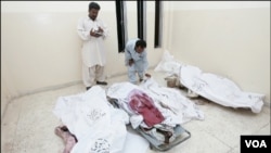 Para petugas Pakistan memeriksa korban tewas dalam bentrokan antarkelompok politik di Karachi (5/7).