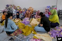 Para pekerja memeriksa produk pakaian di Asnur Konveksi, produsen garmen di Bandung, Jawa Barat, 11 Juli 2024. (Achmad Ibrahim/AP)