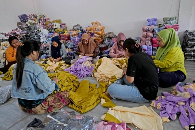 Para pekerja memeriksa produk pakaian di Asnur Konveksi, produsen garmen di Bandung, Jawa Barat, 11 Juli 2024. (Achmad Ibrahim/AP)