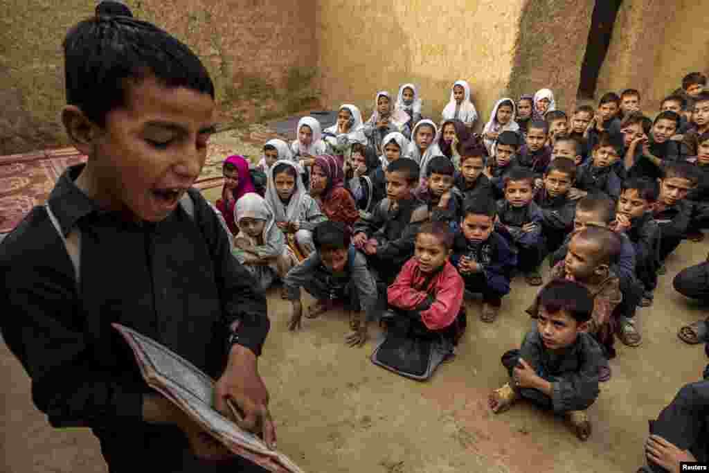 A boy recites from a book during a lesson at a school in a slum on the outskirts of Islamabad, Pakistan.