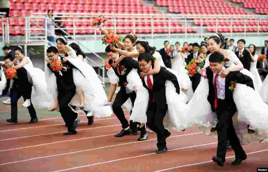 64 orang mahasiswa doktoral di Harbin Institute of Technology yang melakukan nikah massal berlomba lari sambil menggendong pasangannya di Harbin, Heilongjiang, China.