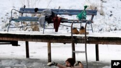 Un hombre nada en las heladas aguas del Lago Dziekanowskie cerca de Lomianski, en Polonia, cuando la temperatura bajó a menos 12 grados centígrados (10 F), el lunes 18 de noviembre de 2021.