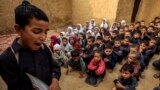 A boy recites from a book during a lesson at a school in a slum on the outskirts of Islamabad, Pakistan.