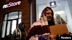 A man holds a sign about selling his place in line before the Apple's new iPhone XS and XS Max go on sale in front of a cell phone store in central Moscow, Russia Sept. 26, 2018.