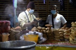 Miguel Menjivar, left, sells bread on a street in San Salvador, El Salvador, before sunrise September 7, 2021, on the day all businesses have to accept payments in Bitcoin, except those lacking the technology to do so.