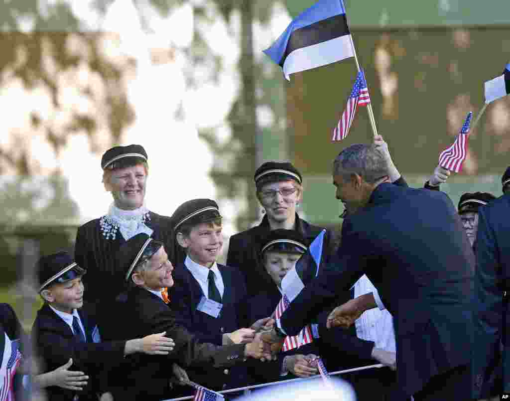 U.S. President Barack Obama, right, greets Estonian school children waving U.S. and Estonian national flags during a welcome ceremony at the Kadriorg Palace in Tallinn, Estonia, Sept. 3, 2014