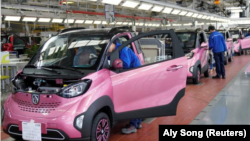 Para pekerja menginspeksi mobil listrik "Baojun E100" di pabrik General Motors di kota Liuzhou, China (foto: dok). 