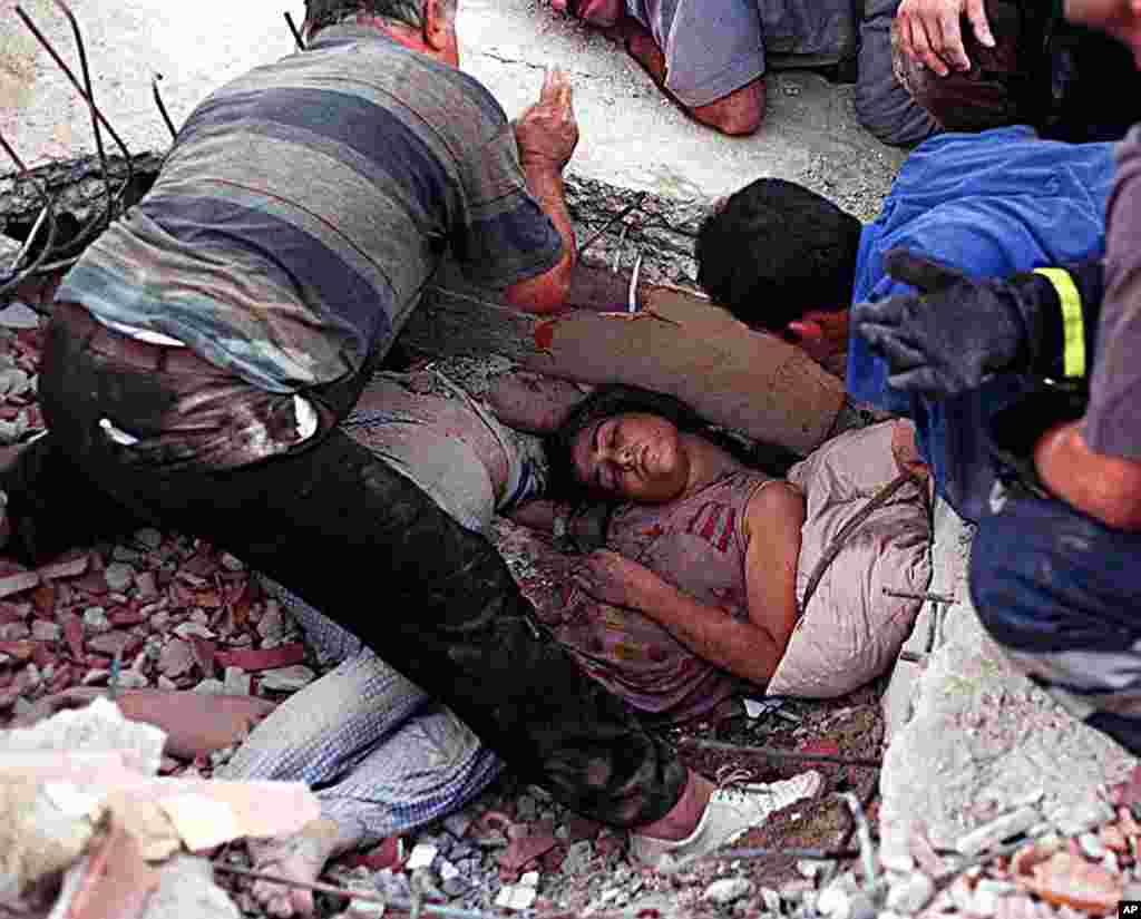 A woman lies trapped in rubble next to a companion as rescue workers try to dig her out of her collapsed home in Istanbul, August 17, 1999. (Reuters)