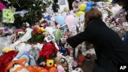 A woman puts a photo of a child on a makeshift memorial in the Sandy Hook Village of Newtown, Conn., as the town mourns victims killed in a school shooting, Dec. 17, 2012.