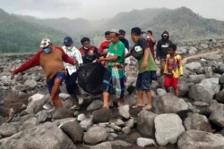 Tim penyelamat dan warga membawa kantong jenazah berisi jenazah korban erupsi Gunung Semeru, di Desa Candi Puro, Lumajang, Jawa Timur, 7 Desember 2021. (Foto: AP)
