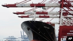 FILE - Containers are loaded onto a cargo ship at the Tianjin port in China. Each year, more than 750,000 people die prematurely from dirty air generated by making goods in one location that will be sold elsewhere. 