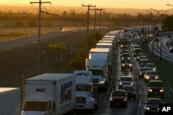 FILE - In this April 9, 2019, photo, trucks wait to cross the border with the U.S. in Ciudad Juarez, Mexico. In a development that could compromise a major trade deal, President Donald Trump has said he is slapping a 5% tariff on all Mexican imports to pressure the country to do more to crack down on the surge of Central American migrants trying to cross the U.S. border.