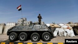 A police trooper stands on an armoured personnel carrier (APC) at a checkpoint in Sanaa, May 14, 2014. 