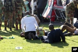 FILE - Injured people are attended to as they lay on the ground following an explosion at a Zanu pf rally in Bulawayo, June, 23, 2018.