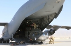 Aerial porters work with maintainers to load a UH-60L Blackhawk helicopter into a C-17 Globemaster III during the withdrawal of forces in Afghanistan, June 16, 2021. (US Army/Sgt. 1st Class Corey Vandiver/Handout via Reuters)