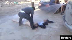  A still image taken from a video posted to a social media website on April 4, 2017, shows a man lying on the ground and being sprayed with water, said to be in the town of Khan Sheikhoun.