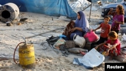 Seorang perempuan Palestina memeriksa barang-barangnya di samping anak-anak setelah serangan Israel di kamp tenda yang menampung orang-orang terlantar di Al-Mawasi, Khan Younis, Jalur Gaza, pada 10 September 2024. (Foto: Reuters)