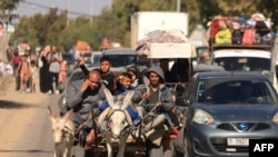 FILE - Riding a donkey drawn cart as family along with hundreds of other Palestinian carrying their belongings flee following the Israeli army's warning to leave their homes and move south before an expected ground offensive, in Gaza City on October 13.