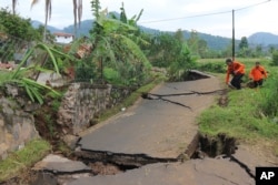 Rescuers navigate through a road badly damaged during Monday's earthquake, in Cianjur, West Java, Indonesia, Nov. 23, 2022.