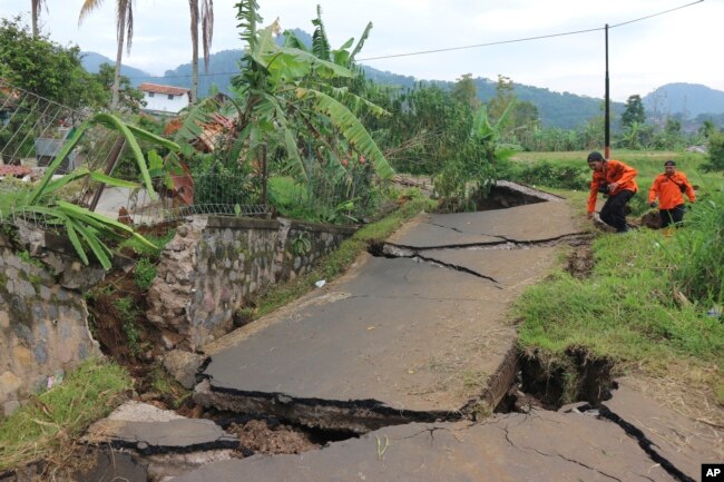 Rescuers navigate through a road badly damaged during Monday's earthquake, in Cianjur, West Java, Indonesia, Nov. 23, 2022.