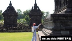 Seorang pekerja menyemprotkan cairan disinfektan di sebuah candi untuk mencegah penyebaran virus corona (Covid-19) di Klaten, Jawa Tengah, 19 Maret 2020. (Foto: Antara via Reuters)