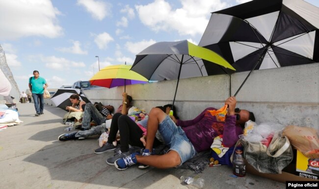 FILE - Immigrants from Guatemala and Cuba seeking asylum in the United States wait on the Matamoros International Bridge, June 28, 2018, in Matamoros, Mexico.