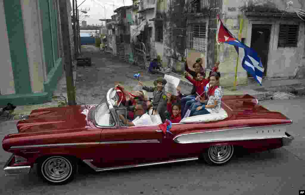 Cuban children, one dressed as Fidel Castro, ride in a classic car during a caravan marking the 57th anniversary of the arrival of Castro and his rebel army in Regla, outside Havana, Cuba, Jan. 8, 1959, after toppling dictator Fulgencio Batista.