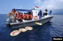 Karangan bunga bertuliskan nama 53 awak kapal selam KRI Nanggala-402 yang tenggelam, diletakkan di atas permukaan laut dari kapal seusai sholat di laut dekat Labuhan Lalang, Bali, 26 April 2021. (Antara Foto / Fikri Yusuf / via Reuters)
