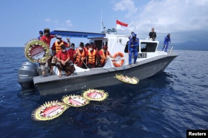 Karangan bunga bertuliskan nama 53 awak kapal selam KRI Nanggala-402 yang tenggelam, diletakkan di atas permukaan laut dari kapal seusai sholat di laut dekat Labuhan Lalang, Bali, 26 April 2021. (Antara Foto / Fikri Yusuf / via Reuters)